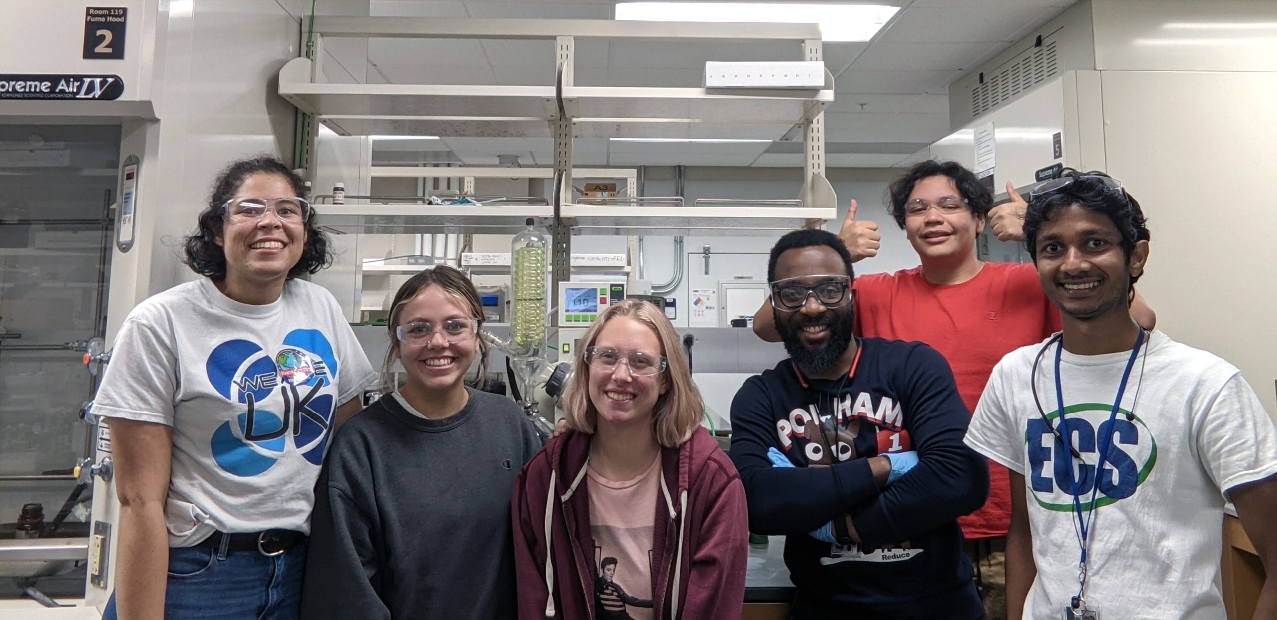 A group of 6 college-aged students smile for the camera in a lab