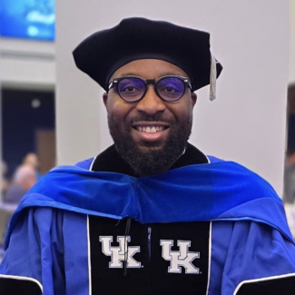 a black man with glasses in gruadtion robes