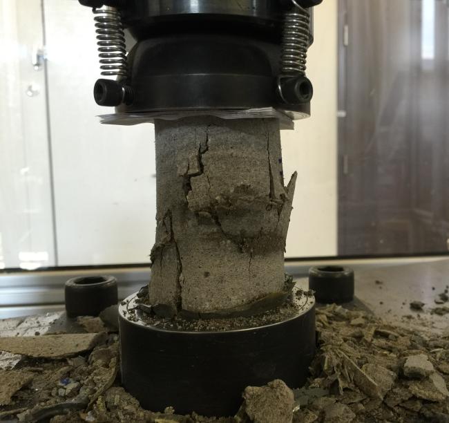 a concrete cylinder is crushed in an instrument to test its strength