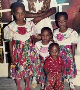 a family photo of 4 black children and their parent - the parent's head has been cropped out of the photo